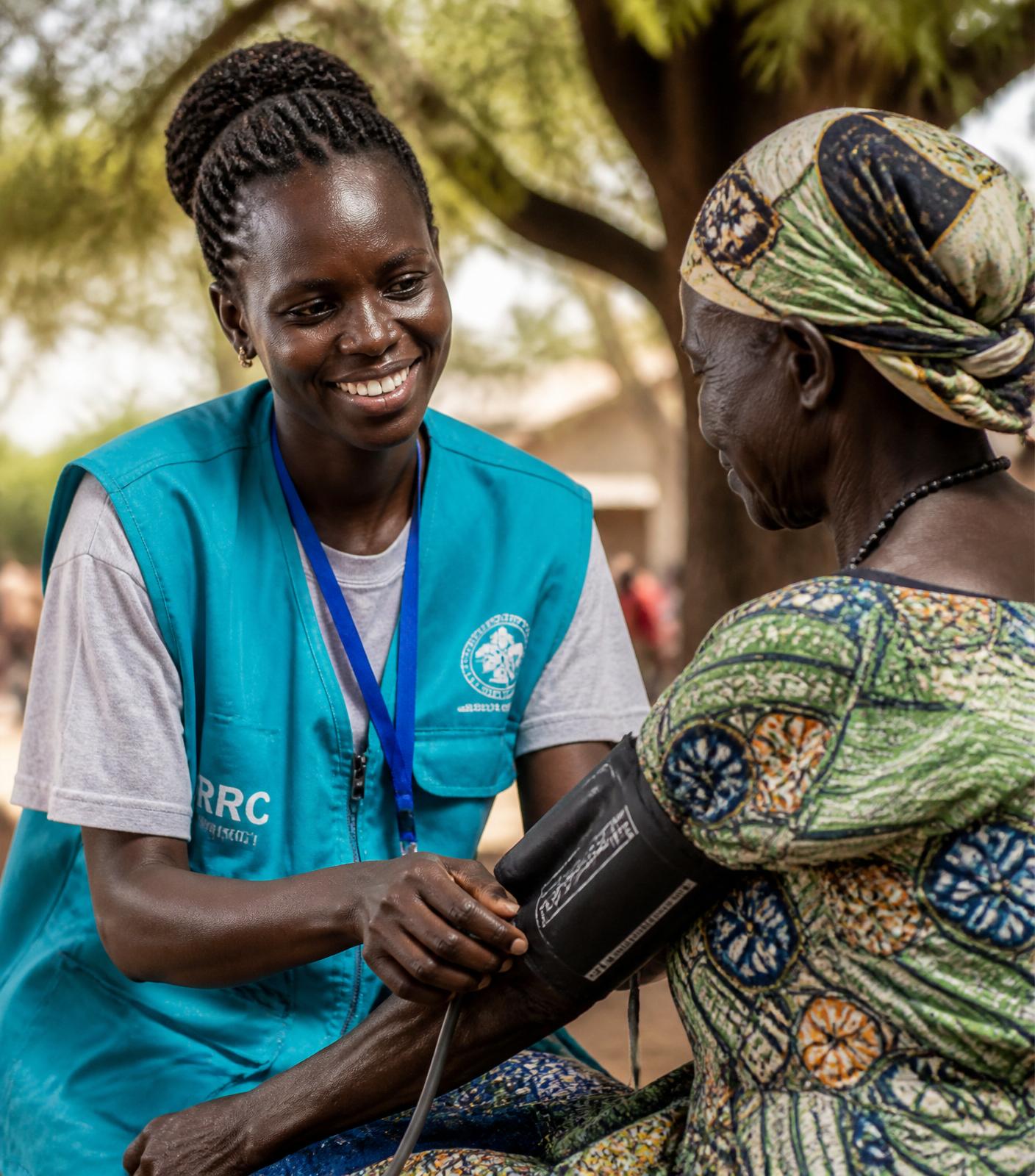 Community health workers meeting under an acacia tree